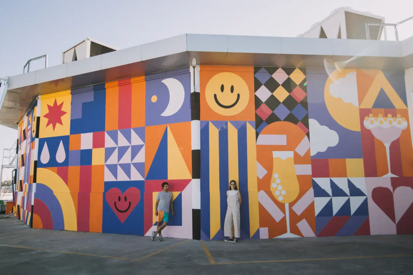 Two people in front of a colourful house